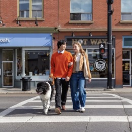 a couple of people and a dog walking across the street