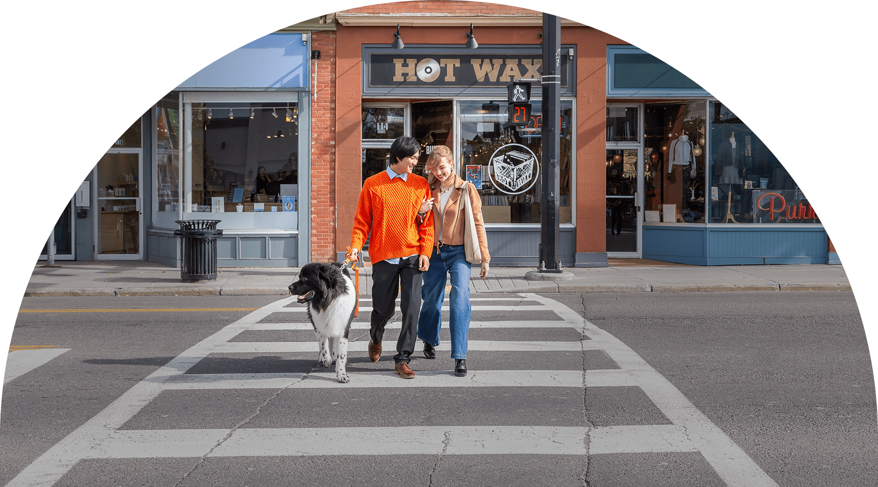 a couple crossing a street walking a dog